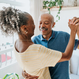 Older couple dancing on a balcony.