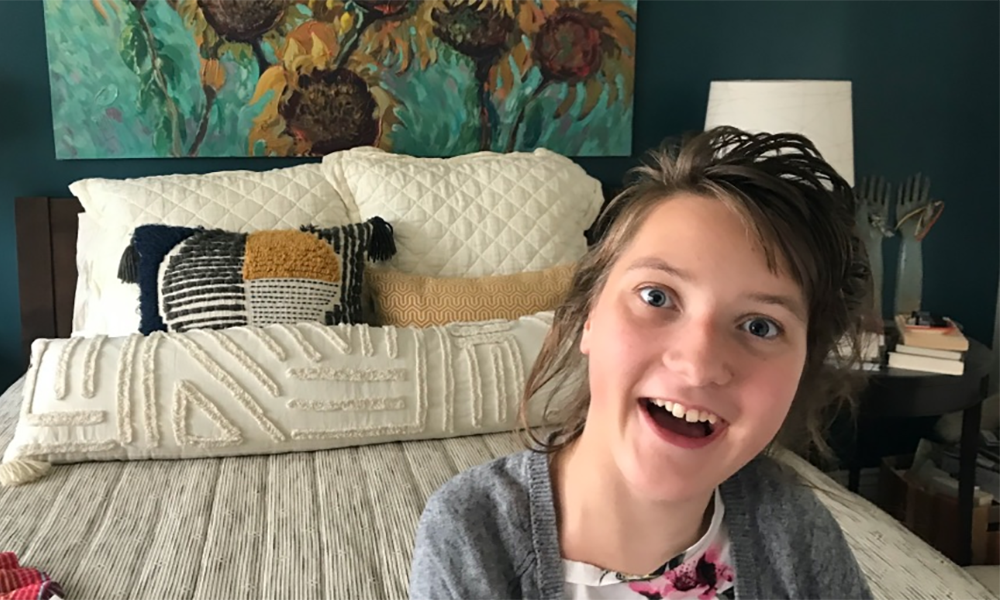 Teenage girl sitting in bedroom
